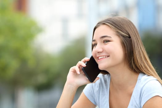 Happy teen talking on mobile phone in the street