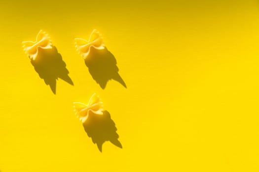 Three pieces of farfalle paste on a yellow background.