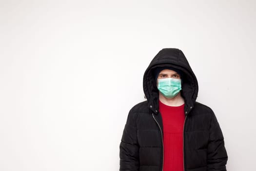 Man with green protective mask on white background. A man with a red sweater and a black jacket.