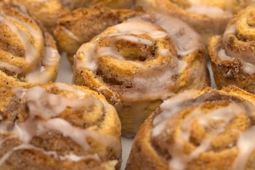 Some delicious cinnamon rolls with white icing on a plate