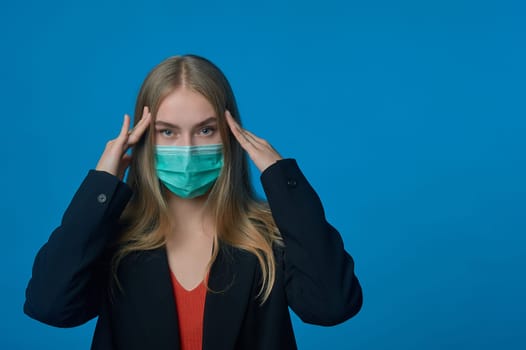 Business woman with a medical mask on her face holding her head. High quality photo
