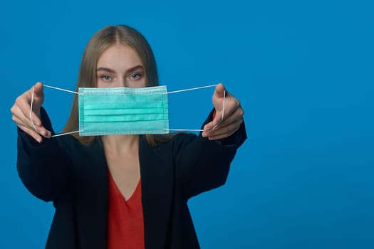 The girl holds a medical mask at arm's length. High quality photo