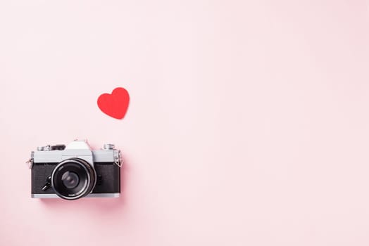 Valentines' day background. Vintage retro camera and red hearts composition greeting card love Valentines day I love photography concept on pink background with copy space. Top View from above