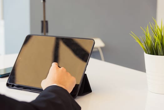 Work from home, Back view of Asian young businessman smile wearing suit video conference call or facetime by smart digital tablet computer he use finger touch on blank screen of tablet on desk