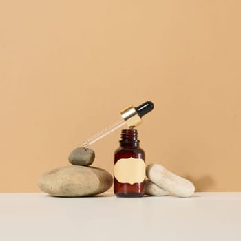 a brown glass bottle with a pipette and a brown label stands on a stone. Container for cosmetics