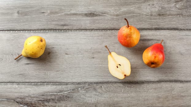 Table top view, ripe pears, one cut in half, on gray wood desk.