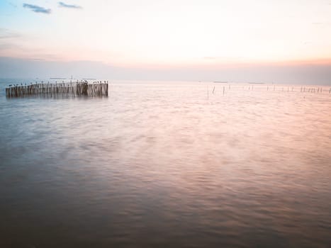 long exposure wooden pole in sea at dusk. Pastel blue and pink sky in Bangpu Thailand