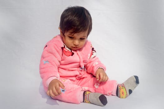 Close-up Portrait of happy Baby Wearing pink Velvet warm clothes on white background. Cute Baby in Bodysuit Autumn or winter fashion Outfit on a sunny day. Pretty little boy. Copy space. Front View