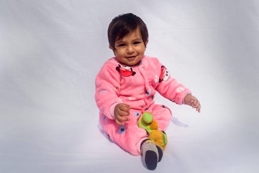 Close-up Portrait of happy Baby Wearing pink Velvet warm clothes on white background. Cute Baby in Bodysuit Autumn or winter fashion Outfit on a sunny day. Pretty little boy. Copy space. Front View