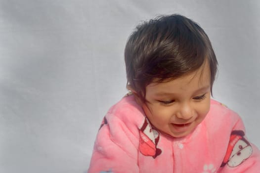 Close-up Portrait of happy Baby Wearing pink Velvet warm clothes on white background. Cute Baby in Bodysuit Autumn or winter fashion Outfit on a sunny day. Pretty little boy. Copy space. Front View
