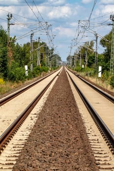 Transit Railroad tracks going through a scenic forested countryside with a blue sky and fluffy clouds above. Macro.
