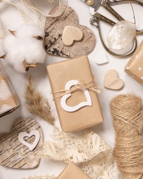 Valentines Day present wrapped in kraft paper and decorated with heart near lace, pampass grass and cotton flowers top view. Spring rustic, cottage chic or bohemian concept