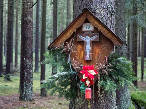 Memorial cross on a tree trunk in the forest