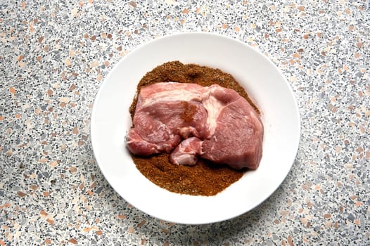 A piece of spiced meat in a plate before frying. High quality photo