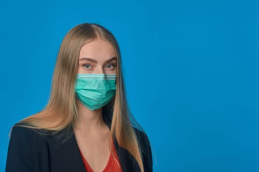 Portrait of a girl in a medical mask on a blue background. High quality photo