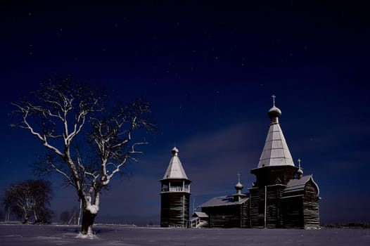 Wooden ancient temple at night in winter on a tree background. High quality photo