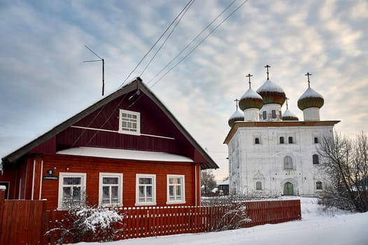 Village hut in winter on the background of the temple. High quality photo