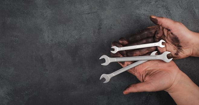 Holding wrench tools in the hands covered with fuel oil, repairing tools, industrial worker, copy spac