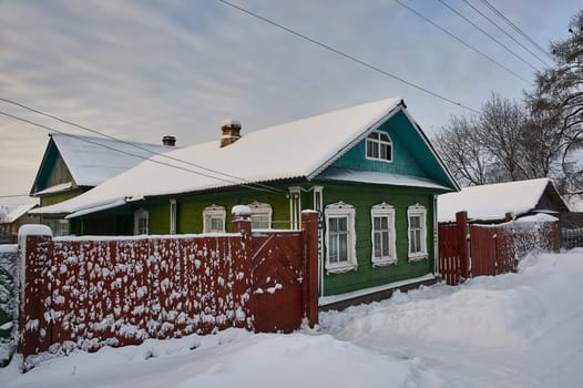 Village hut in winter on the background of the temple. High quality photo