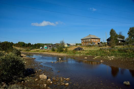 Shallow river on the background of the village. High quality photo