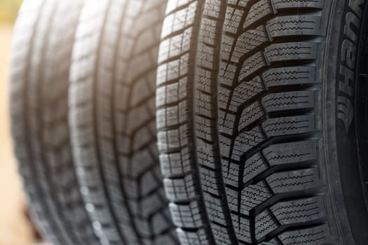 Set of winter tires prepared to be changed on a vehicle in workshop. Closeup view of new rubber car wheels. Structure of unused automobile part in detail.