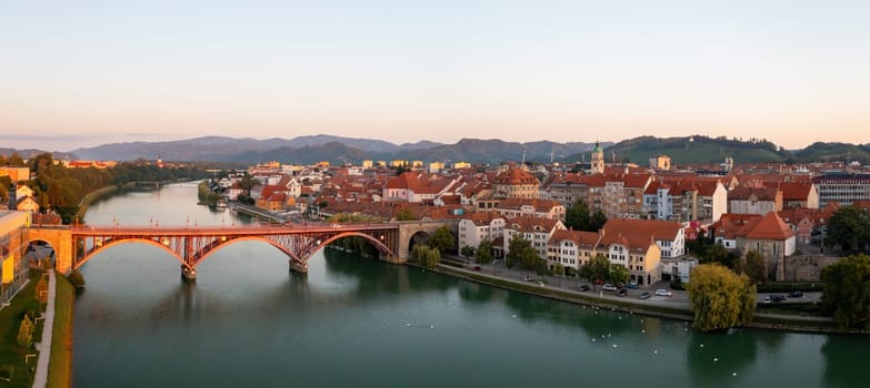 Panoramic view of Maribor city in summer at sunrise from above. Historical city in Slovenia with space for text. Bridge with river in morning sunlight.