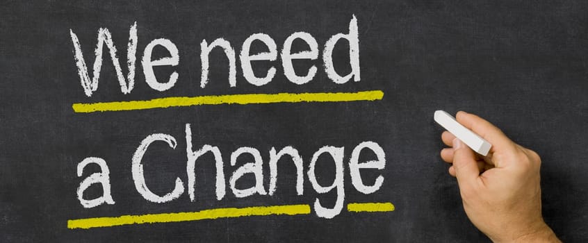 Text written on a blackboard - We need a change
