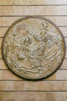 ALMATY, KAZAKHSTAN - NOVEMBER 8, 2019: voluminous medallion depicting dancing girls against the background of the sun at Auezov Theater Almaty Metro subway Station.