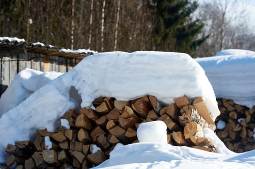 Wood piled in a woodpile under the snow in winter. High quality photo
