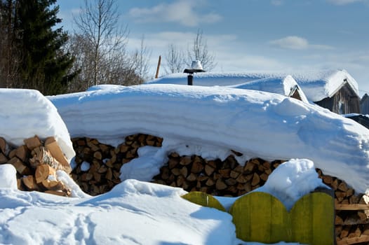 Wood piled in a woodpile under the snow in winter. High quality photo