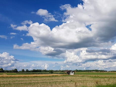 Beautiful shot of a big white clouds and little house. field in front.