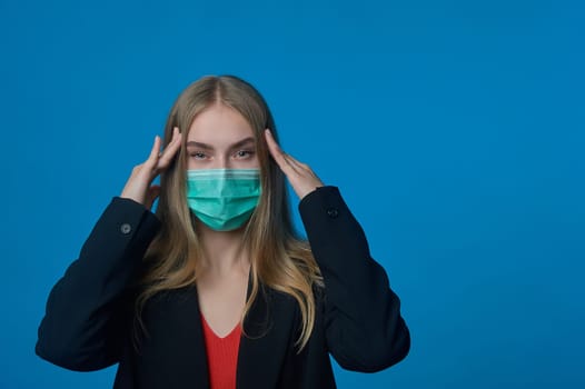 Business woman with a medical mask on her face holding her head. High quality photo
