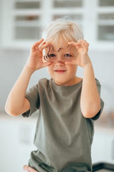 Little caucasian boy holding and looking through a Christmas cookie cutter. Kid with blond hair is playing with cookie cutter. Praparation for Christmas holiday. Kids being kids and having fun.