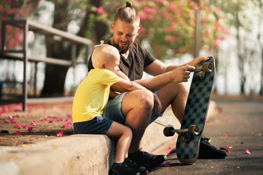 Father is spending quality time with with his little son in skate park Springtime. Family real time
