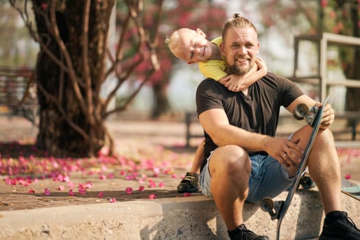 Father is having fun together with his little son in skate park Springtime. Portrait