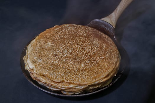 stack of hot fried pancakes in a frying pan