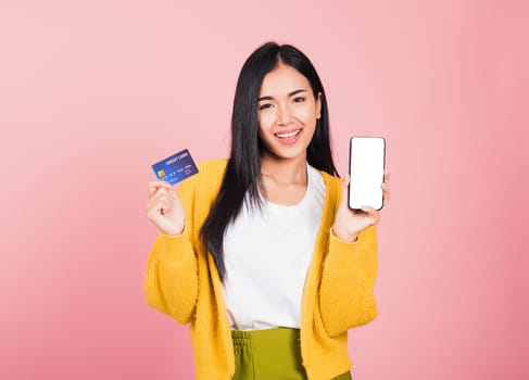 Happy Asian portrait beautiful cute young woman excited smiling hold mobile phone and plastic debit credit bank card, studio shot isolated on pink background, female using smartphone online shopping
