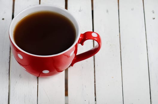 Coffee in vintage red cup on wooden background