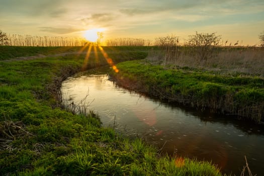 A curving river with a green shore and sunset, Stankow, Lubelskie, Poland
