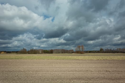 Plowed farmland and dark rainy clouds in the sky, Nowiny, Poland
