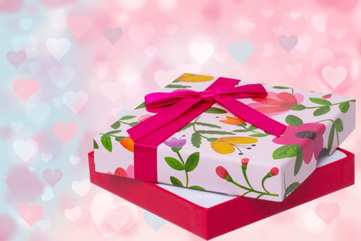 Happy Valentine or Mothers Day card template. Beautiful colorful present box over abstract light pink blue pastel background with hearts. Space fort ext design.