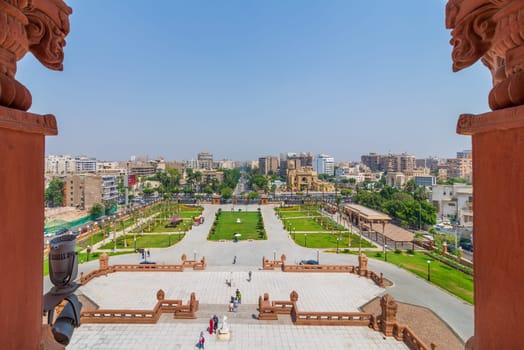 Cairo, Egypt- July 30 2020: View of garden of Baron Empain Palace with Heliopolis district in the far end framed by two decorated pillars at the roof of the palace