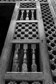 Black and white angle view of wooden carved decorations of interleaved wooden door - Mashrabiya - in abandoned building