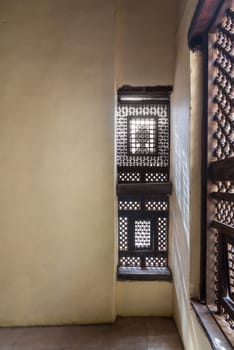 Corner of two Interleaved grunge wooden ornate windows - Mashrabiya - in stone wall in abandoned building