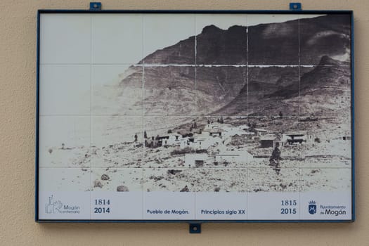 CRAN CANARIA, MOGAN - NOVEMBER 15, 2019:.Old photo on a wall tile on a house in Mogan. Picture shows the old town of Mogan, Gran Canaria, Spain