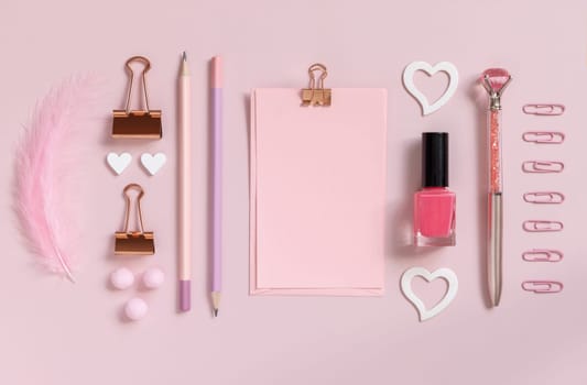 Pink paper card with clip, school girlish accessories and hearts on pastel pink close up, blank card mockup. Girly workplace. Back to school and valentines day concepts
