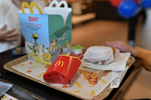 PARIS, FRANCE -DECEMBER 05, 2021: McDonald's food with kids box on the table. Family around.