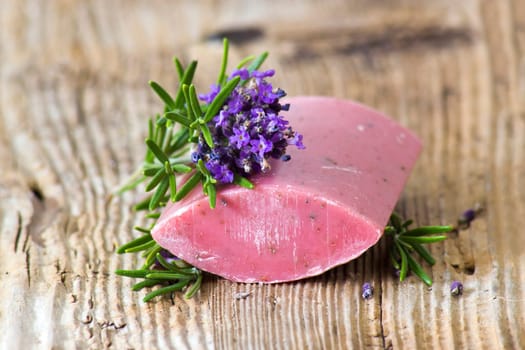 bar of natural soap, lavender flowers and rosemary on old wooden background