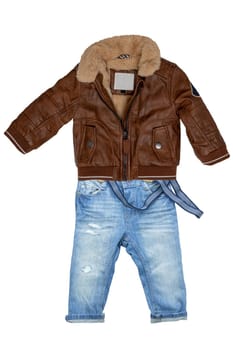 Closeup of a trendy stylish brown leather jacket with fur and a blue denim pants or trousers for child boy isolated on a white background. Jeans autumn fashion.