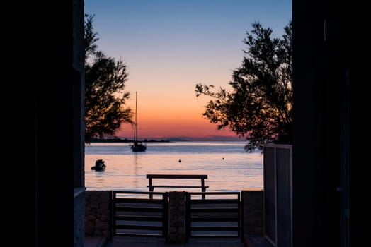 View from the yard to the sea, sailing boat and a beautiful sunset.
